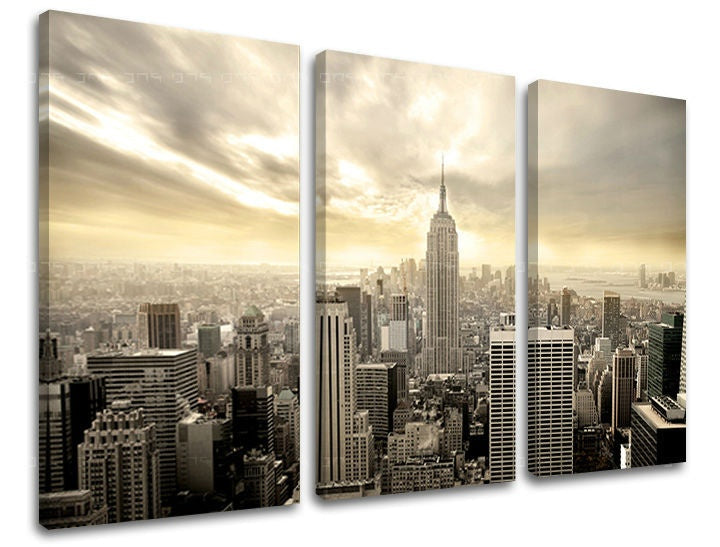 Třídílný obraz na plátně zachycuje panoramatický pohled na New York s mrakodrapy a zataženou oblohou ve zlatavých tónech, Papilora.