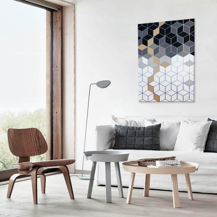 Moderní obraz s geometrickým vzorem kostek v odstínech šedé, černé a bílé s akcenty zlaté, visící v minimalistickém interiéru nad dřevěnou konzolí s vázou a svíčkou Papilora.