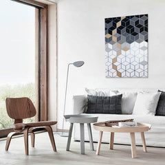 Moderní obraz s geometrickým vzorem kostek v odstínech šedé, černé a bílé s akcenty zlaté, visící v minimalistickém interiéru nad dřevěnou konzolí s vázou a svíčkou Papilora.