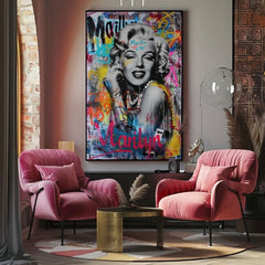 Obraz Marilyn Monroe v pop-art stylu s barevnými graffiti a zlatými detaily visí v moderním interiéru nad dřevěnou konzolí s vázou a svíčkou Papilora.