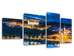 Čtyřdílný obraz na plátně zachycuje noční panorama Bratislavy s hradem a osvětlenými ulicemi, s viditelným dřevěným rámem Papilora.