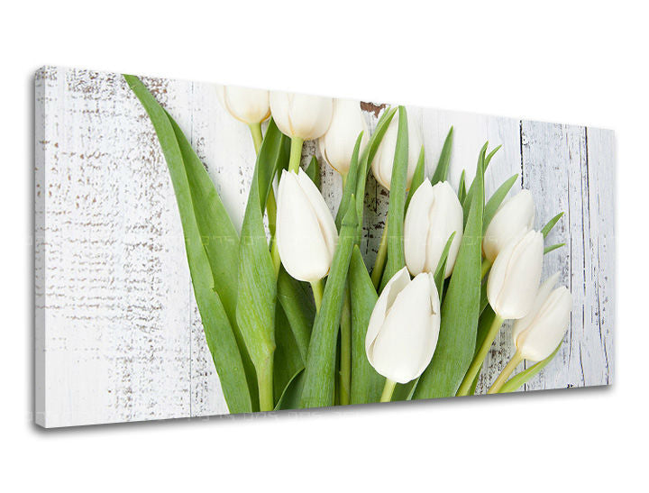 Na plátně je zobrazeno seskupení bílých tulipánů s jasně zelenými listy, položených na patinovaném bílém dřevěném podkladu, Papilora.