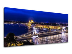 Umělecké dílo na plátně zobrazuje noční panorama Budapešti s osvětleným Řetězovým mostem a budovou parlamentu, vše v tmavě modrých a zlatých tónech, Papilora.