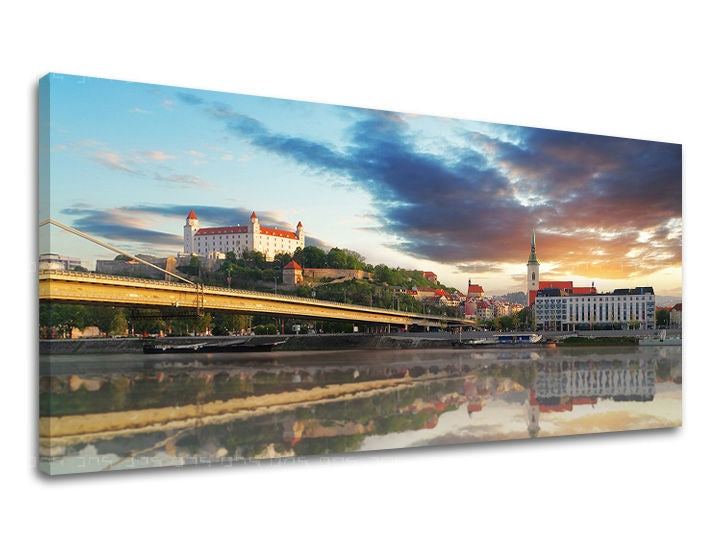 Na plátně je zachyceno panorama Bratislavy s hradem a mostem přes Dunaj za západu slunce, s odrazy na vodní hladině Papilora.