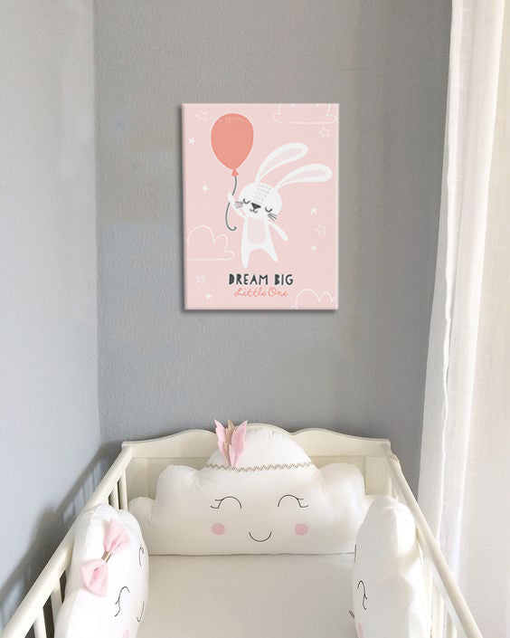 Na plátně je zobrazen roztomilý bílý králík držící růžový balónek na světle růžovém pozadí s mraky a hvězdami, s textem „DREAM BIG Little One“, Papilora.