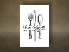 Na bílém plátně jsou vyobrazeny elegantní příbory a nápis „Bon Appetit“ v černé barvě, s viditelným dřevěným rámem Papilora.