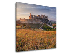 Kompozice zachycuje hrad na kopci s dramatickou oblohou a zlatavou trávou v popředí, Papilora.