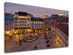 Na plátně je zachyceno večerní panorama Bratislavy s osvětleným náměstím a hradem v pozadí, v teplých odstínech fialové a žluté, Papilora.