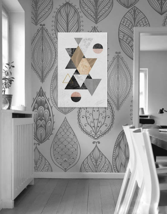 Abstraktní obraz s geometrickými tvary v šedé, černé a zlaté barvě visí v moderním interiéru nad dřevěnou konzolí s vázou a svíčkou Papilora.