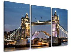 Třídílné plátno zobrazuje ikonický Tower Bridge v Londýně za soumraku s rozsvícenými světly a zvednutým mostem, vše na dřevěném rámu Papilora.