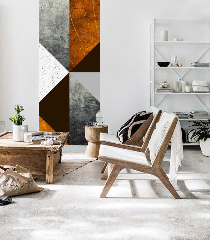 Abstraktní geometrické tvary v šedé, bílé, hnědé a oranžové barvě visí v moderním interiéru nad dřevěnou konzolí s vázou a svíčkou Papilora.