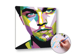 Na plátně je zobrazen pop-artový portrét Leonarda DiCapria v živých barvách, s viditelným dřevěným rámem Papilora.