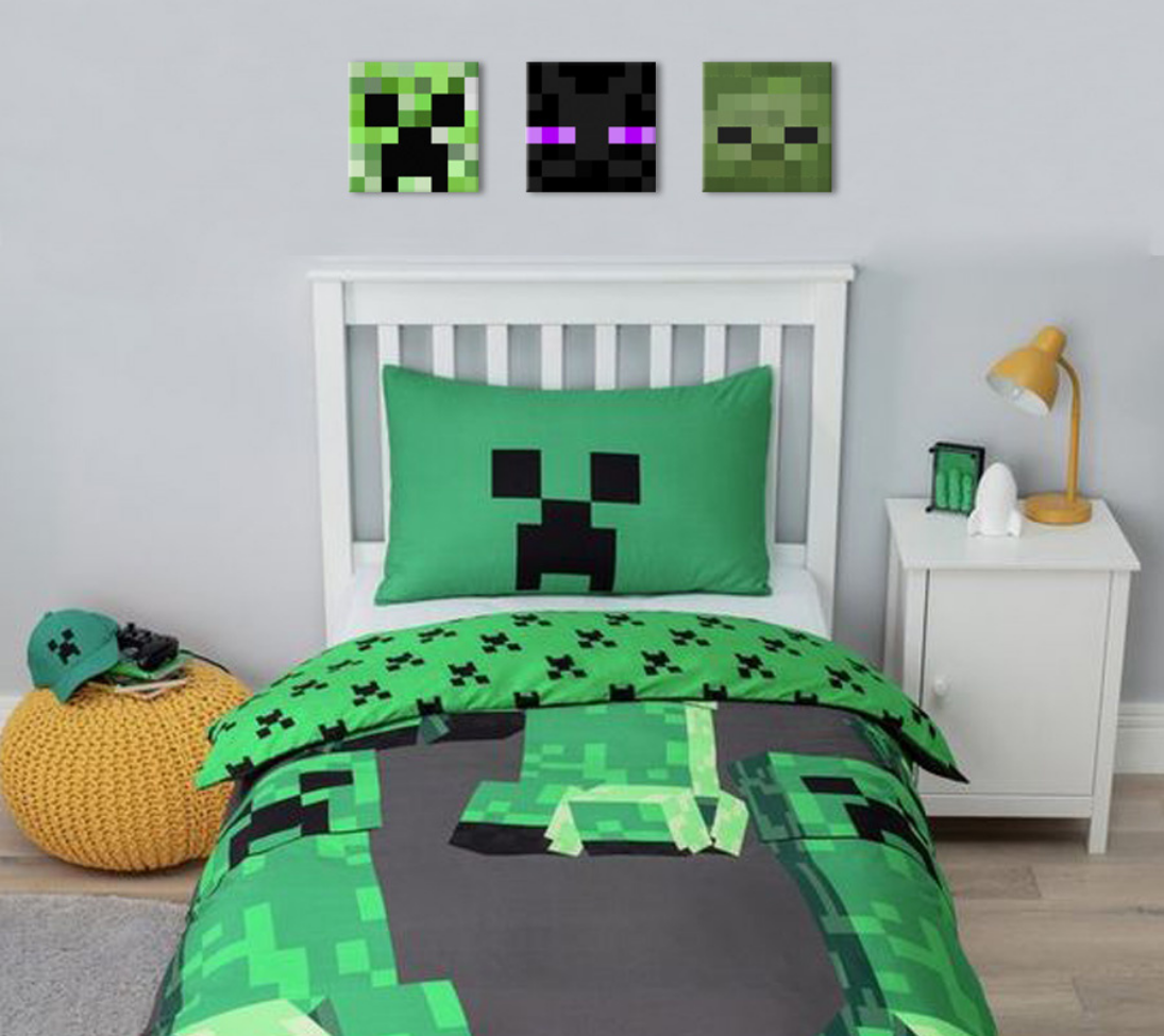 Tři čtvercové obrazy s pixelovými hlavami postav ze hry Minecraft, včetně zeleného Creepera, jsou zavěšeny nad dětskou postelí s hračkami, Papilora.