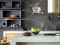 Nástěnné hodiny ve tvaru šálku kávy s nápisem 'Coffee Time' a zrnky kávy, v lesklém stříbrném provedení, visí v moderním stylovém interiéru nad dřevěnou konzolí s vázou a svíčkou Papilora.