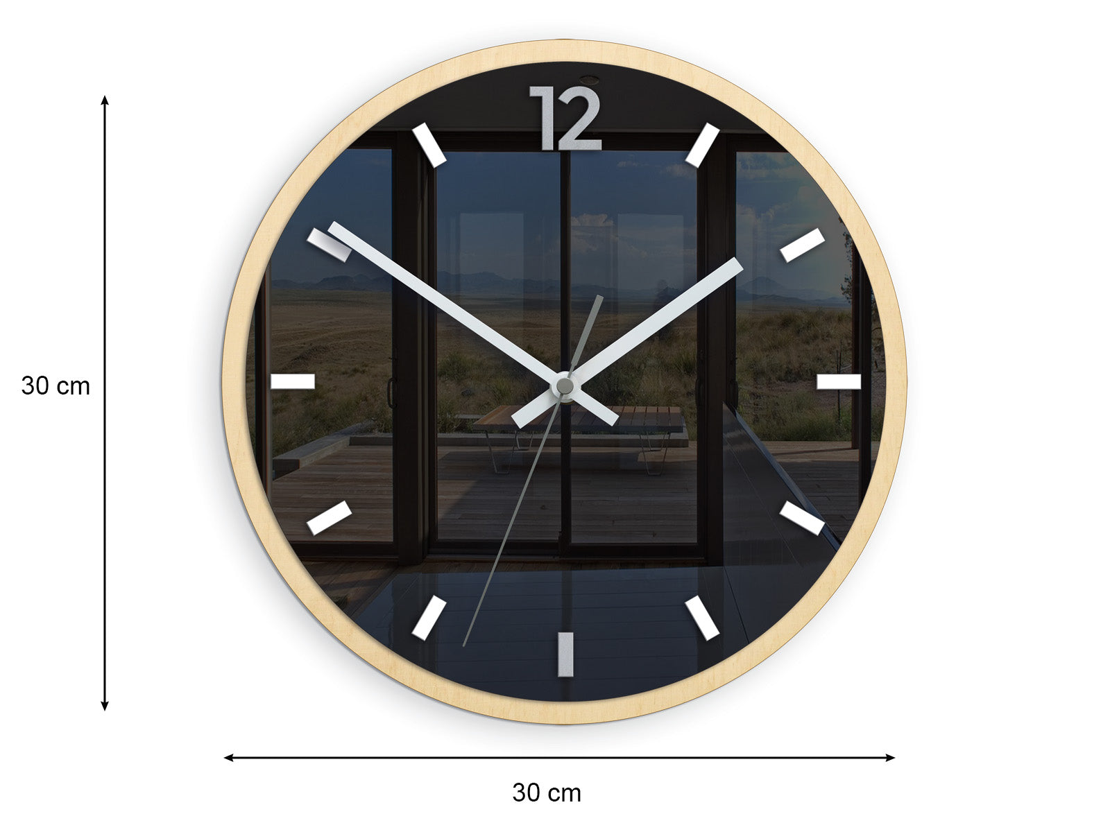 Moderní nástěnné hodiny s minimalistickým designem a motivem krajiny, zavěšené nad dřevěnou konzolí s vázou a svíčkou, Papilora.