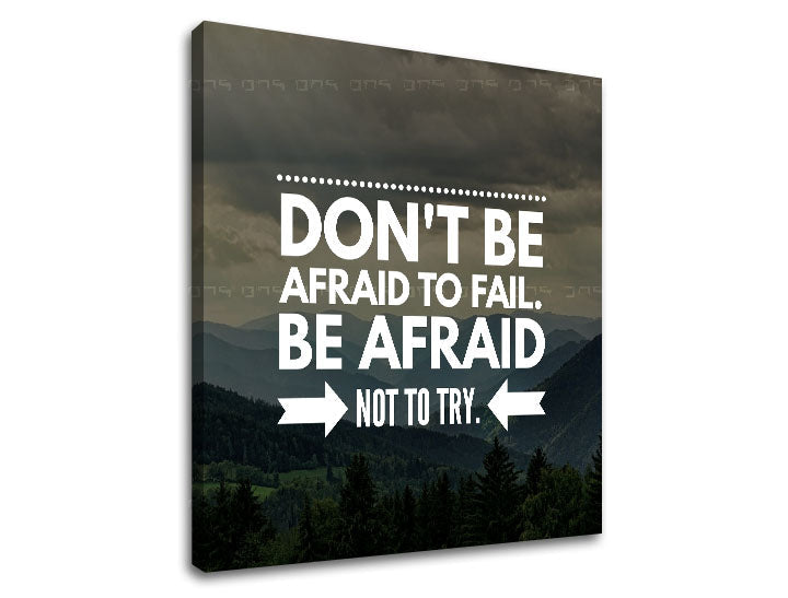 Plátno s motivačním citátem „DON'T BE AFRAID TO FAIL. BE AFRAID NOT TO TRY.“ na pozadí hor a lesů, s viditelným dřevěným rámem, Papilora.
