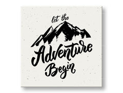Obraz s citátem 'Let the Adventure Begin' a horami visí v moderním interiéru nad dřevěnou konzolí s vázou a svíčkou Papilora.