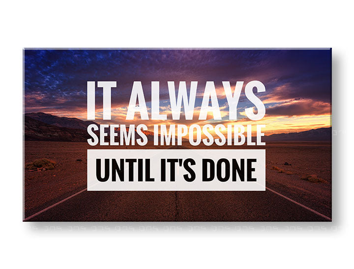 Obraz s citátem „IT ALWAYS SEEMS IMPOSSIBLE UNTIL IT’S DONE“ a krajinou západu slunce, zavěšený v moderním interiéru nad dřevěnou konzolí s vázou a svíčkou, Papilora.