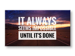 Obraz s citátem „IT ALWAYS SEEMS IMPOSSIBLE UNTIL IT’S DONE“ a krajinou západu slunce, zavěšený v moderním interiéru nad dřevěnou konzolí s vázou a svíčkou, Papilora.