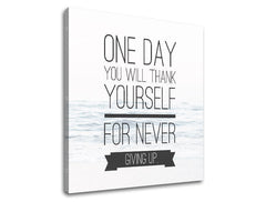 Plátno s motivačním citátem „ONE DAY YOU WILL THANK YOURSELF FOR NEVER GIVING UP“ na pozadí klidné mořské hladiny, viditelné z boku s dřevěným rámem Papilora.