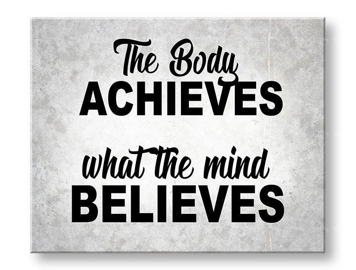Obraz s motivačním citátem „The Body Achieves What The Mind Believes“ visí v moderním interiéru nad dřevěnou konzolí s vázou a svíčkou Papilora.