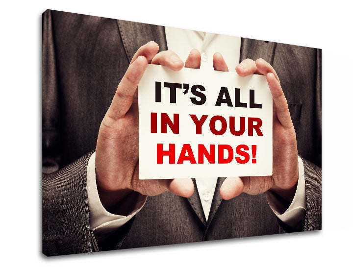 Plátno s potiskem zobrazuje ruce držící nápis „IT'S ALL IN YOUR HANDS!“ v černé a červené barvě, s viditelným dřevěným rámem Papilora.