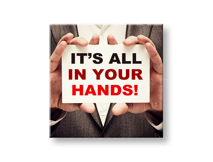 Obraz s motivačním citátem „IT'S ALL IN YOUR HANDS!“ zavěšený v moderním interiéru nad dřevěnou konzolí s vázou a svíčkou Papilora.