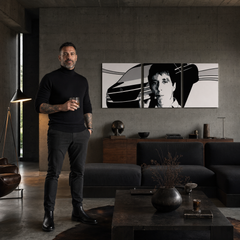 Černobílý triptych s motivem Tonyho Montany a vozu Mercedes-Benz visí nad dřevěnou konzolí s vázou a svíčkou v moderním interiéru Papilora.