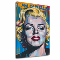 Ručně malované plátno s portrétem Marilyn Monroe v pop-art stylu s výraznými zlatými akcenty a nápisem "I AM CAPITALIST" na modro-žlutém pozadí, viditelný dřevěný rám Papilora.