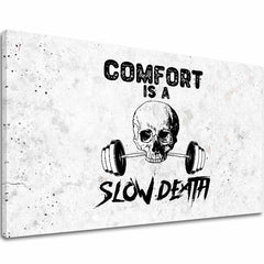 Na plátně je vyobrazena černobílá lebka držící činku v ústech s textem 'COMFORT IS A SLOW DEATH' na pozadí připomínajícím beton, Papilora.