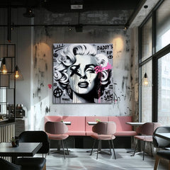 Obraz s portrétem Marilyn Monroe v pop-art stylu, s černými a růžovými detaily na šedém pozadí, visí v moderním interiéru nad dřevěnou konzolí s vázou a svíčkou Papilora.