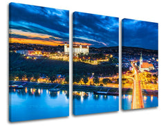 Třídílný obraz na plátně zachycuje noční panorama Bratislavy s hradem a Dunajem v modrých a oranžových tónech, Papilora.