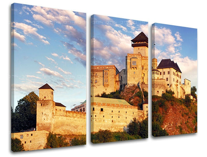 Třídílný obraz na plátně zobrazuje majestátní Trenčínský hrad tyčící se na skále pod modrou oblohou s mraky, Papilora.