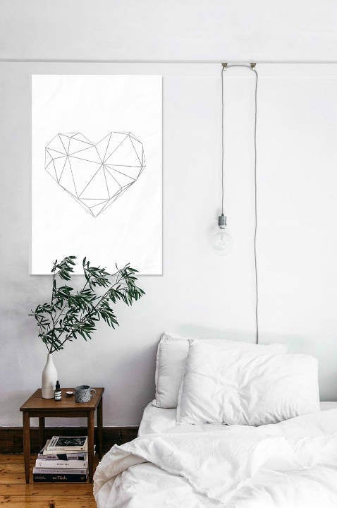 Obraz s geometrickým srdcem v šedé a bílé barvě visí v moderním interiéru nad dřevěnou konzolí s vázou a svíčkou Papilora.