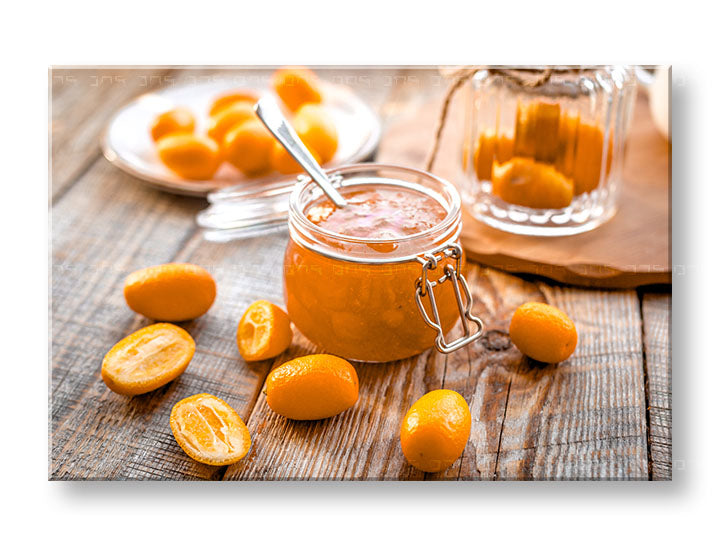 Obraz s džemem z kumquatu a čerstvými plody na dřevěném stole, v oranžových a hnědých tónech, visí nad dřevěnou konzolí s vázou a svíčkou Papilora.
