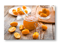 Obraz s džemem z kumquatu a čerstvými plody na dřevěném stole, v oranžových a hnědých tónech, visí nad dřevěnou konzolí s vázou a svíčkou Papilora.