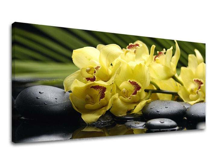 Nádherný tisk na plátně zobrazuje žluté orchideje s tmavými kameny na pozadí zelených listů, vše s viditelným dřevěným rámem Papilora.