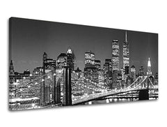 Černobílý tisk nočního panoramatu New Yorku s Brooklynským mostem a osvětlenými mrakodrapy na plátně s viditelným dřevěným rámem Papilora.