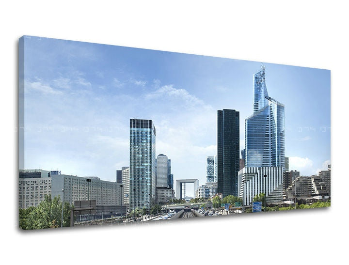 Na plátně je zobrazeno panoráma moderního města s mrakodrapy pod modrou oblohou, s viditelným dřevěným rámem Papilora.