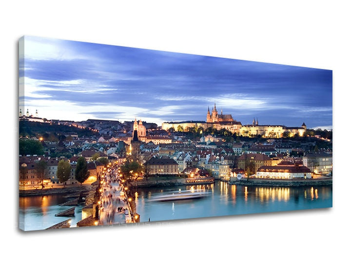 Noční panorama Prahy s osvětleným Karlovým mostem a Pražským hradem pod modrou oblohou na plátně Papilora.