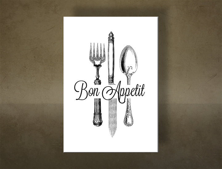Na bílém plátně jsou vyobrazeny elegantní příbory a nápis „Bon Appetit“ v černé barvě, s viditelným dřevěným rámem Papilora.
