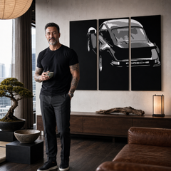 Umělecké dílo s černobílým motivem vozu Porsche visící v moderním interiéru nad dřevěnou konzolí s vázou a svíčkou, Papilora.