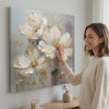 Žena si prohlíží obraz Květinový svět na plátně Potěšení pro vaše smysly 60x60 cm na stěně ve stylovém světlém interiéru | Papilora (SKU XOBMDFL022E1)