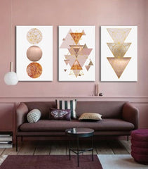 Moderní interiér s růžovou stěnou, nad hnědou pohovkou visí tři plátna s geometrickými tvary, doplňuje je váza a svíčka na konzoli Papilora.