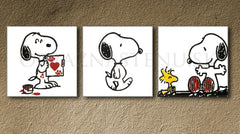 Tři ručně malovaná plátna s černobílými motivy Snoopyho a Woodstocka na bílém pozadí, s červenými akcenty, jsou viditelná na dřevěném rámu Papilora.